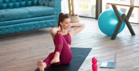 Home sports. Strong millennial woman doing abs exercises in front of laptop computer indoors